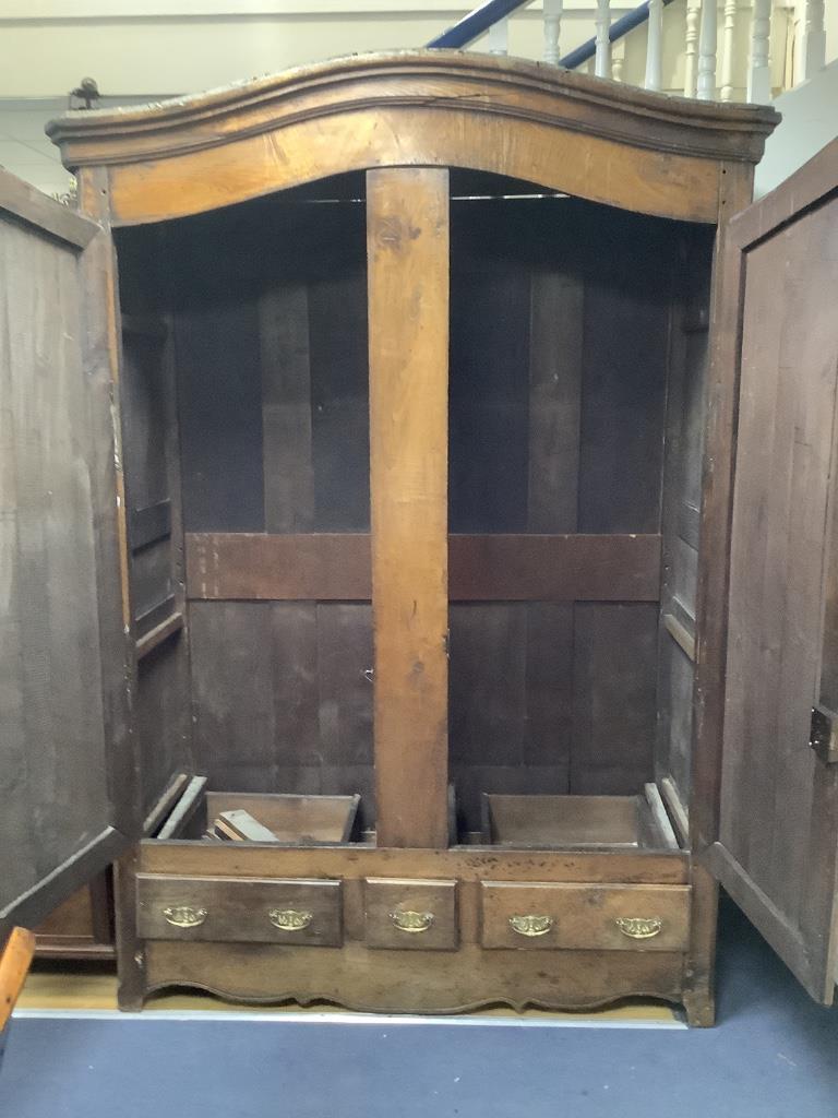 A large French knock-down armoire, with twin panelled doors over two long and one short central drawer, with polished brass mounts and handles, 18th century, width 160cm, depth 62cm, height 223cm